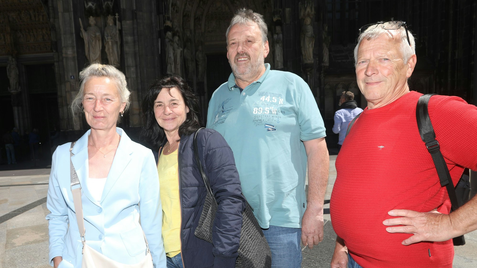Zu sehen sind von links nach rechts Petra, Claudia, Klaus und Theo. Sie stehen auf der Domplatte vor dem Kölner Dom und schauen in die Kamera.