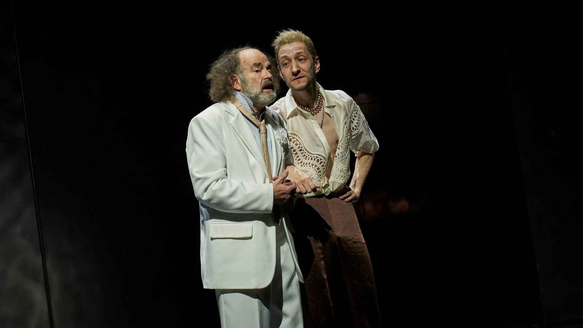 Martin Reinke steht im weißen Anzug neben Alexander Angeletta im weit geöffneten, gemusterten Hemd.