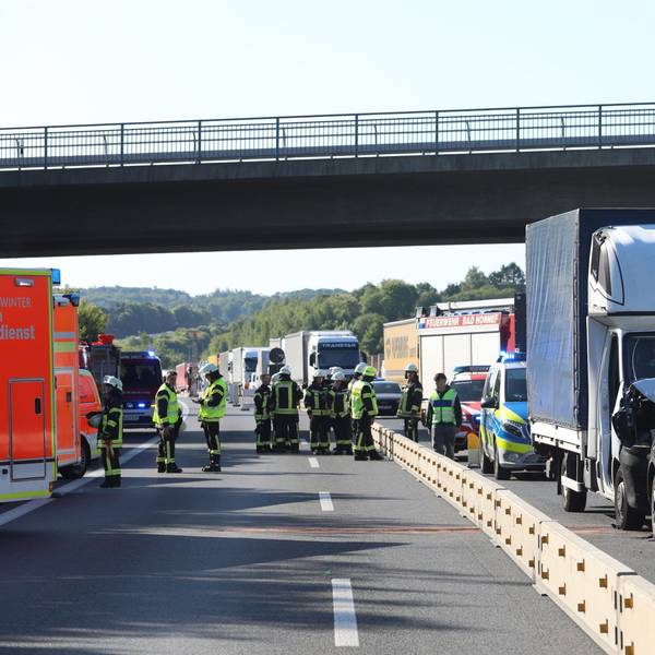 Ein Transporter und ein Pkw sind zusammengestoßen, dahinter staut sich der Verkehr, auf den gesperrten Spuren links daneben stehen Feuerwehrleute und Einsatzfahrzeuge.