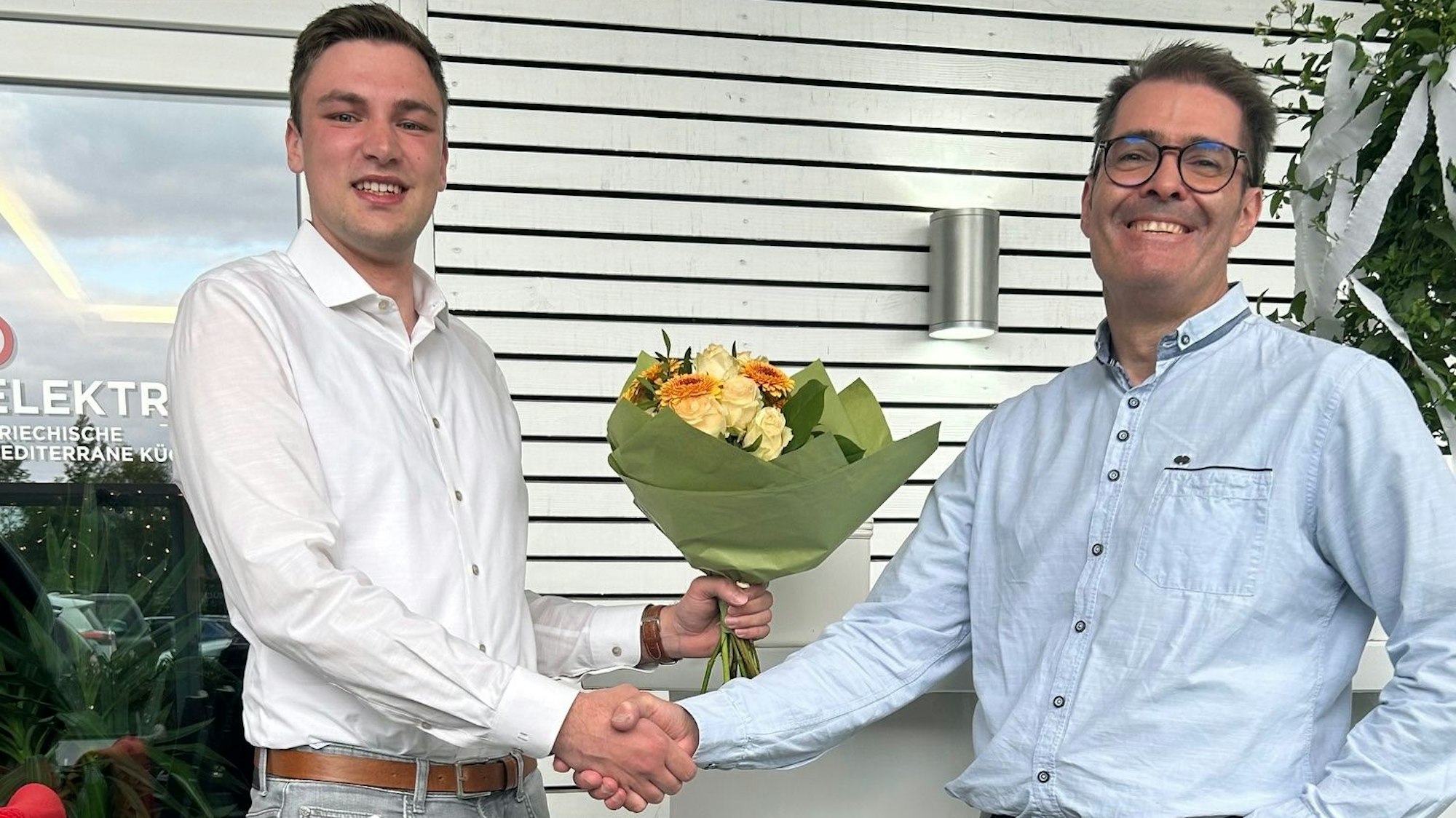 Lukas Krüger (l.) schüttelt die Hand von Oliver Totter und überreicht ihm einen Blumenstrauß.