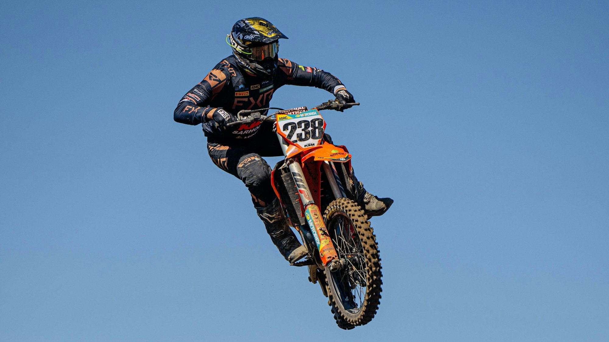 Szene aus einem Motocross-Rennen, bei der ein Fahrer mit seiner Maschine in die Luft springt.