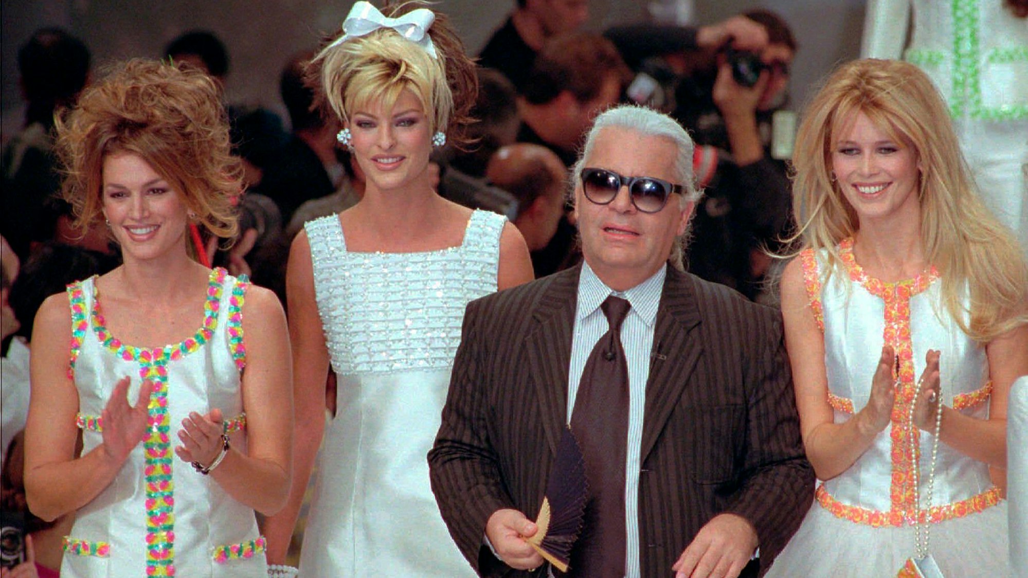 Der deutsche Designer Karl Lagerfeld schließt sich den Models Cindy Crawford (v.l) aus den USA, Linda Evangelista aus Kanada, und Claudia Schiffer aus Deutschland nach der Präsentation seiner Frühjahr-Sommer-Kollektion 1996 für Chanel an. (Archivbild)