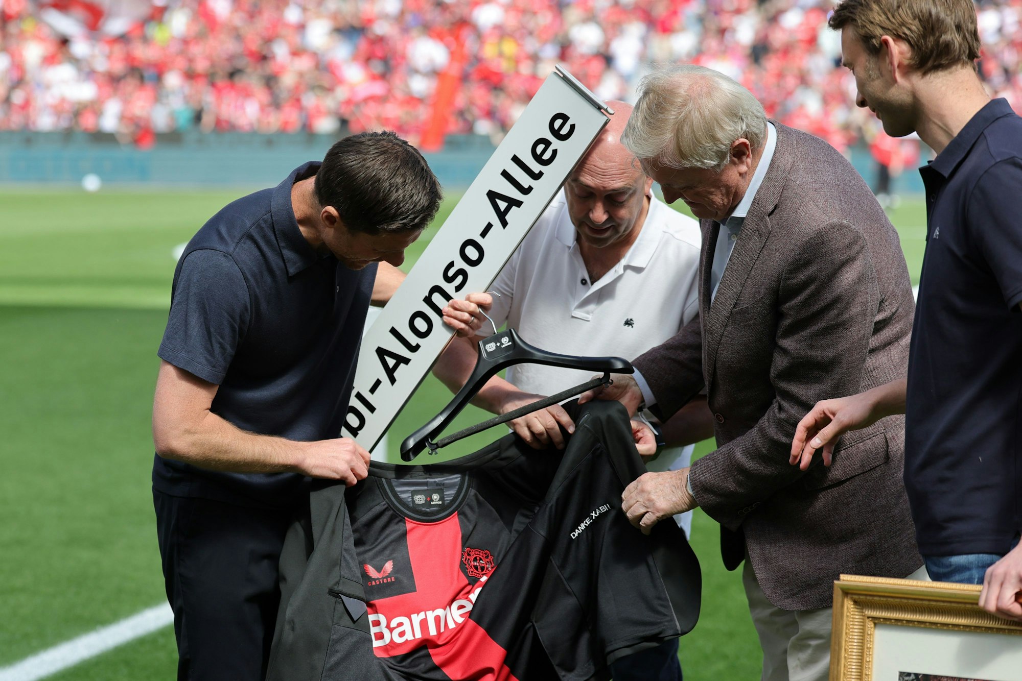 Leverkusens Trainer Xabi Alonso (l-r) steht bei seiner Verabschiedung mit Fernando Carro de Prada, Leverkusens Vorsitzender der Geschäftsführung, Werner Wenning, ehemaliger Vorstandsvorsitzender der Bayer AG, und Simon Rolfes, Leverkusens Geschäftsführer Sport, auf dem Platz
