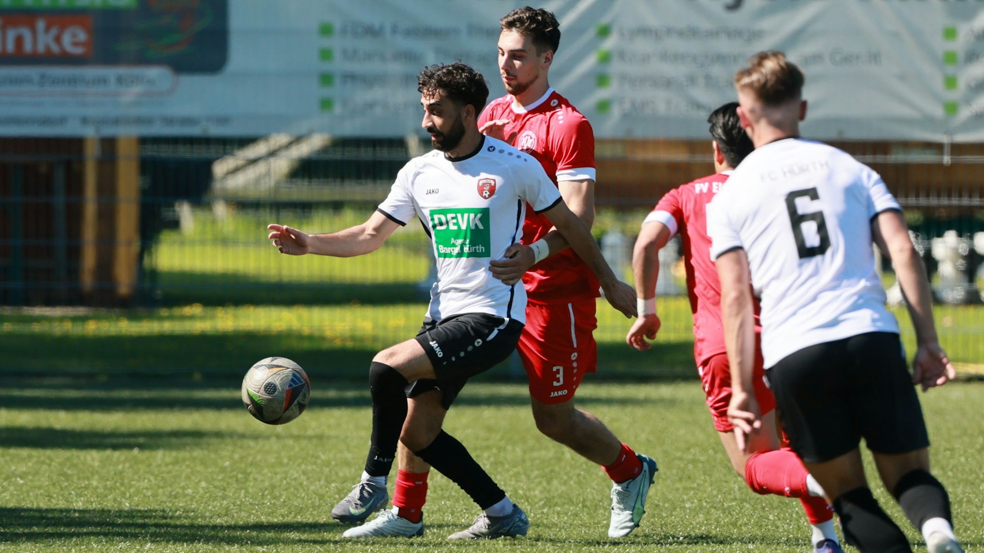 Das Foto zeigt einen Hürther Spieler im weißen Trikot, der den Ball vor seinem Gegenspieler im Rücken abschirmt.