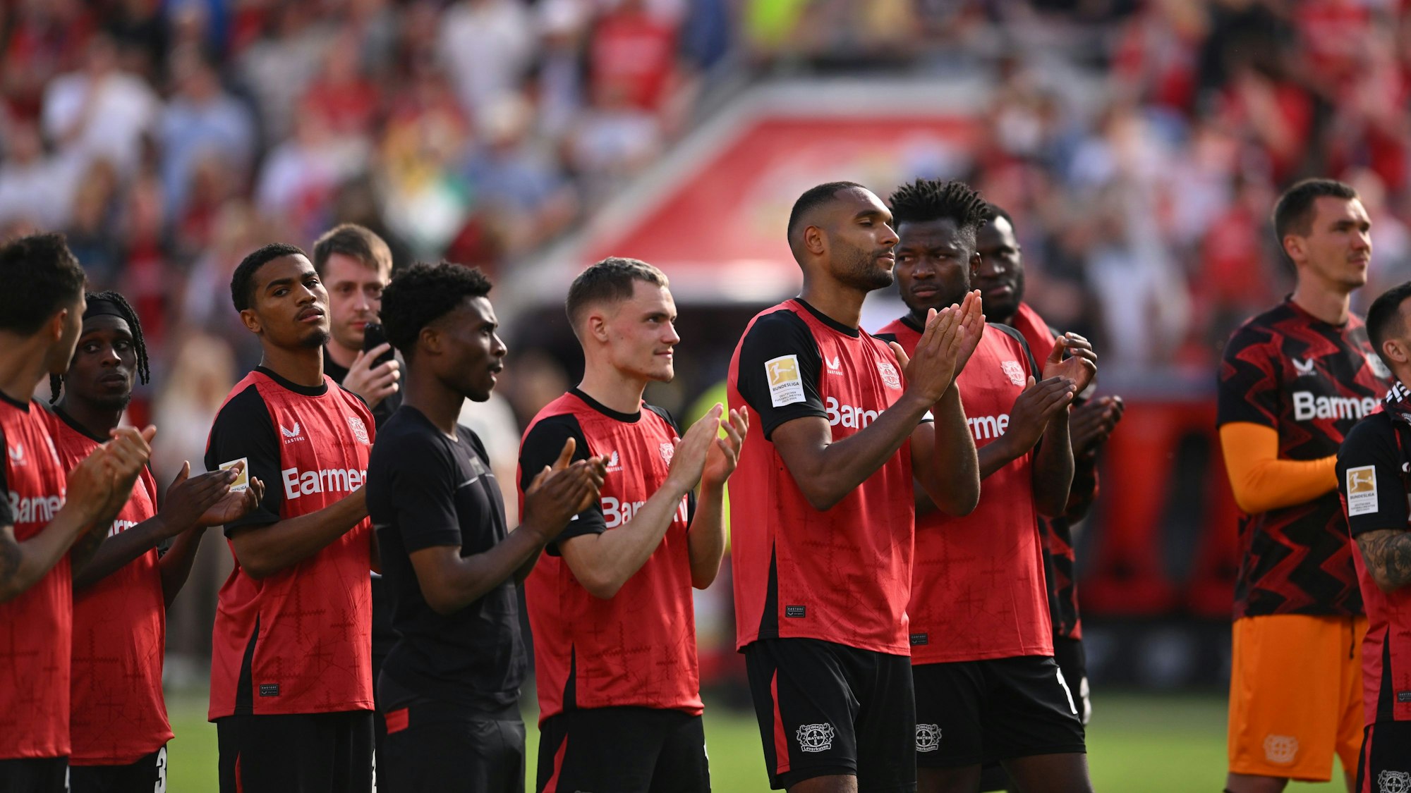 Das Bild zeigt Spieler von Bayer 04 Leverkusen nach dem Spiel gegen Borussia Dortmund, die sich bei den Fans bedanken.