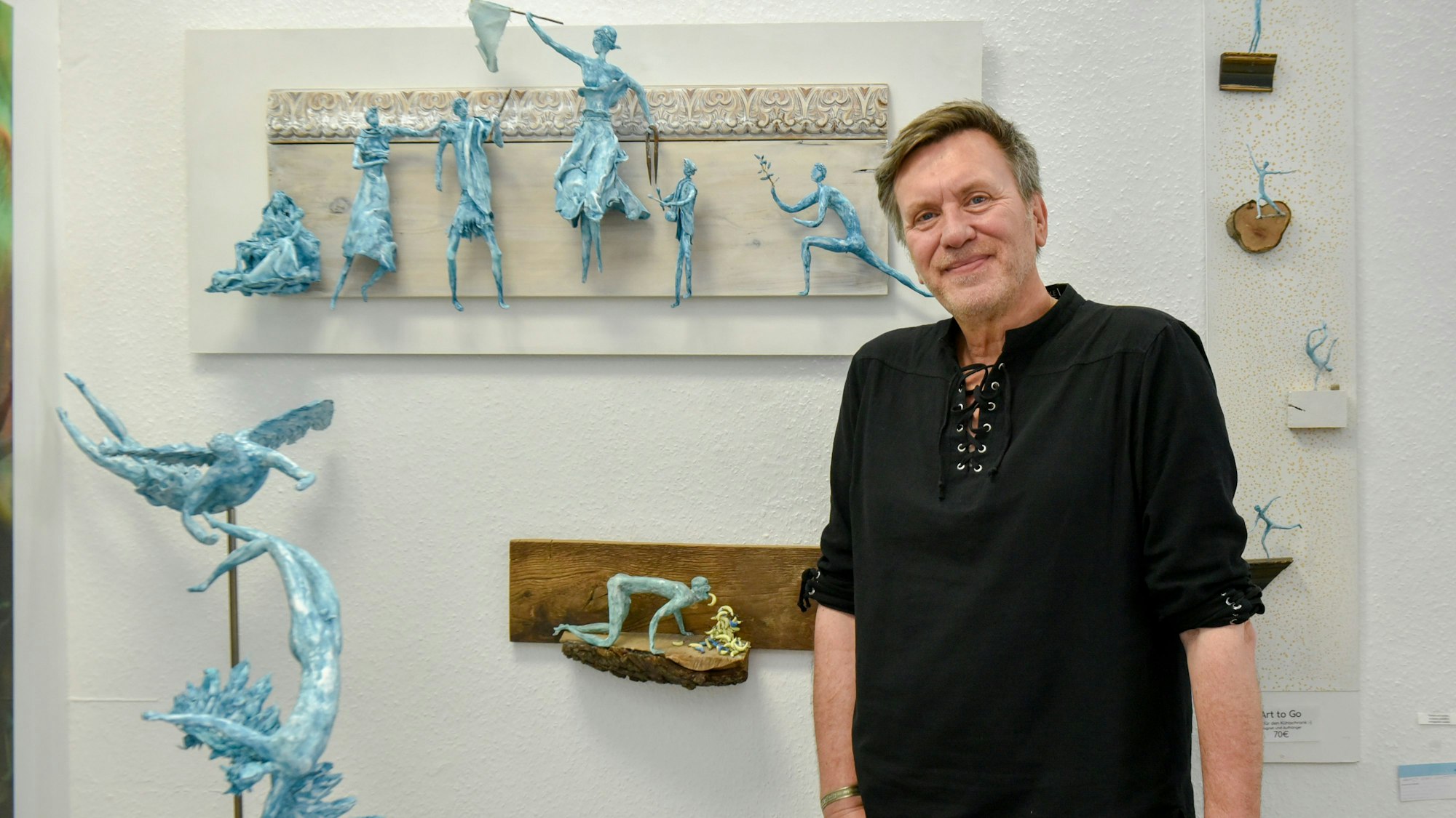 Andre Duront steht vor seinen Skulptren, die dank Magneten an der Wand hängen.