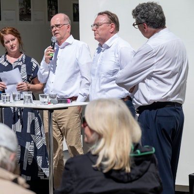 Auf dem Bild sind drei Kölner OB-Kandidaten der Grünen, SPD und CDU und die beiden Moderatoren des KSTA an einem Stehtisch zu sehen.