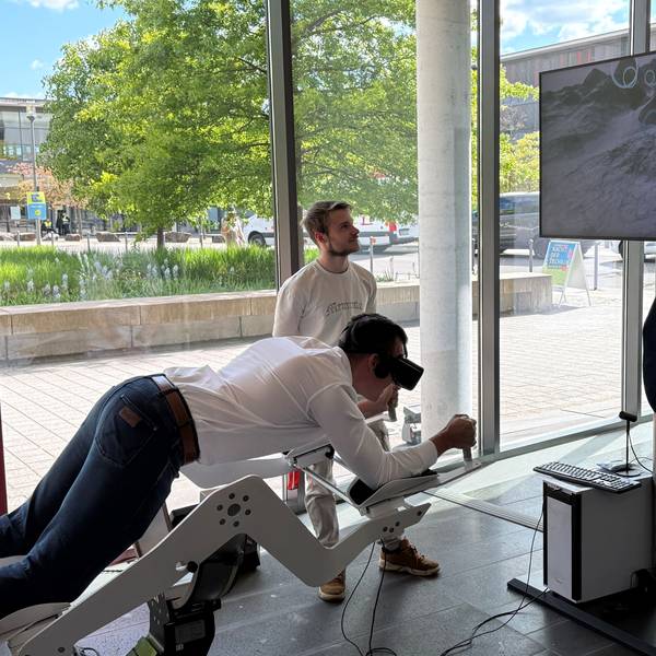 Ein Besucher liegt auf dem Flugsimulator und trägt eine VR-Brille.