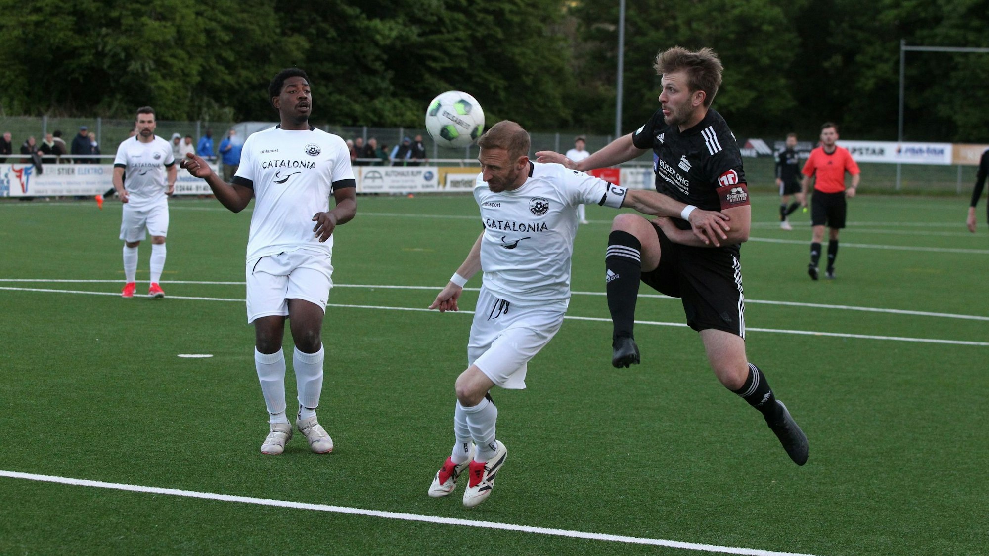 Moritz Hartmann köpft einen Ball, von hintern nähert sich Nierfelds damaliger Kapitän Stephen Kinnen. Bessenichs Ex-Spieler Samson Sayongo beobachtet die Szene erstaunt.
