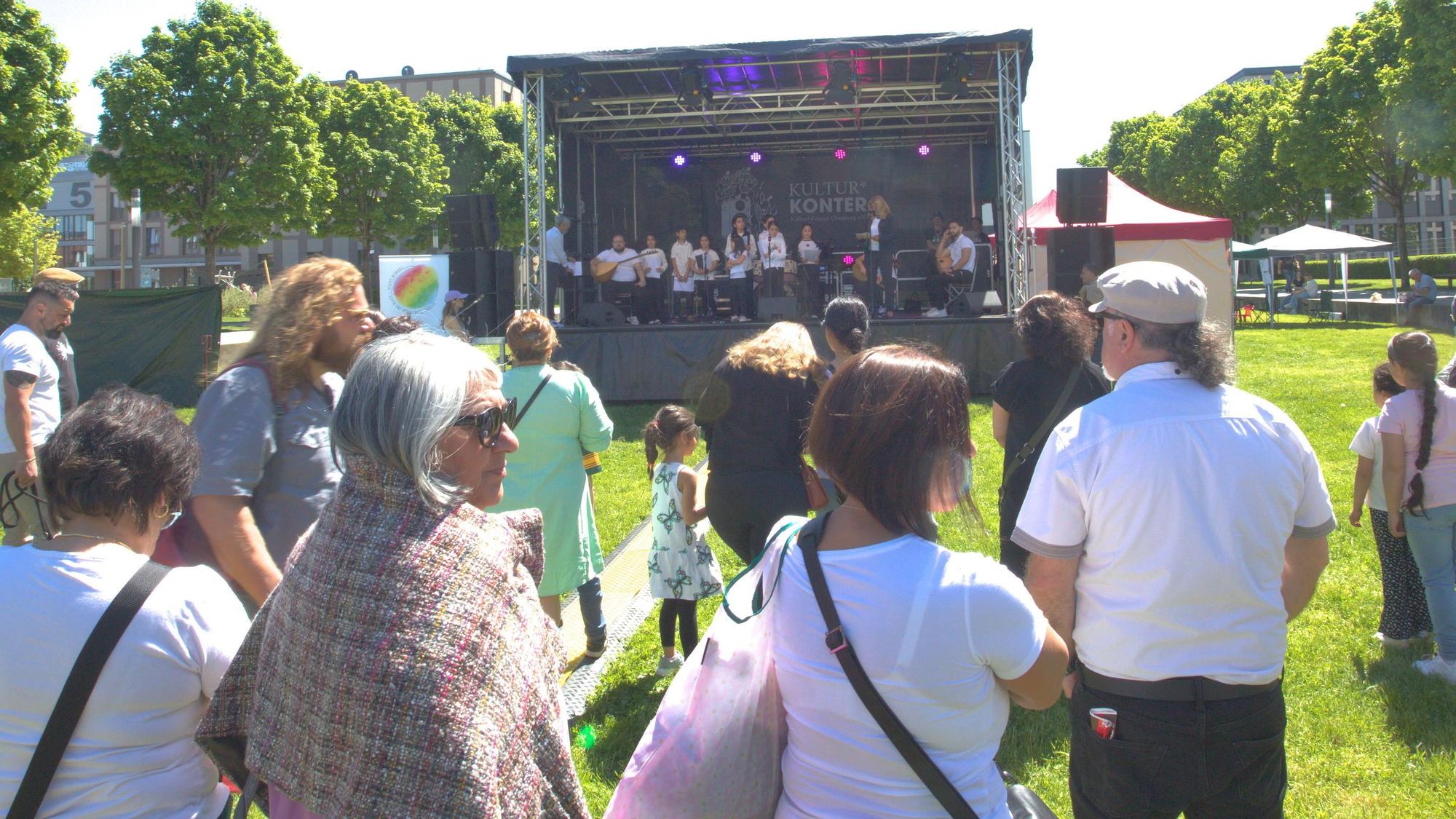 Vor der aufgebauten Bühne im Gummersbacher Stadtgarten, hören Besucher des Festivals dem Chor der anatolischen Stimme zu.