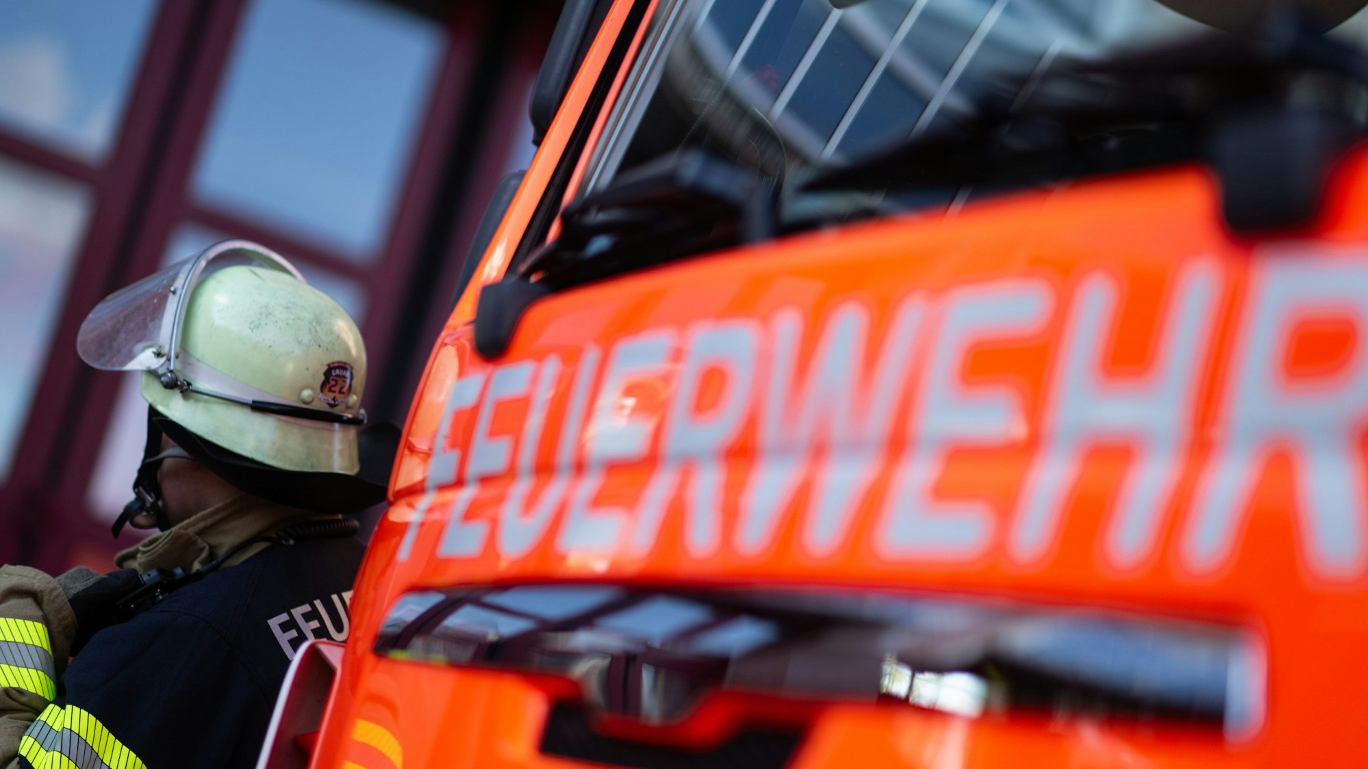 Eine Einsatzkraft der Feuerwehr steht neben einem Einsatzfahrzeug der Feuerwehr