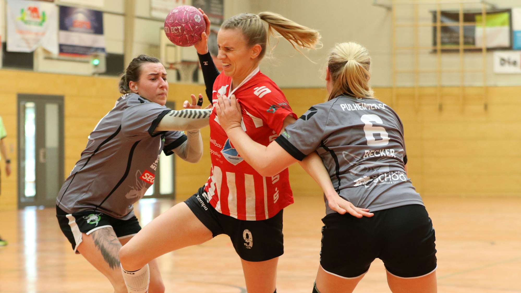 Das Bild zeigt Corinna Schmitz, wie sie sich entschlossen gegen zwei Gegenspielerinnen durchsetzt.