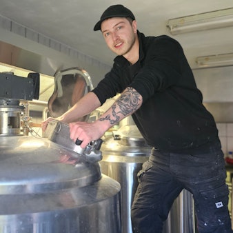 Braumeister Till Verse steht an einem Bottich aus Edelstahl.