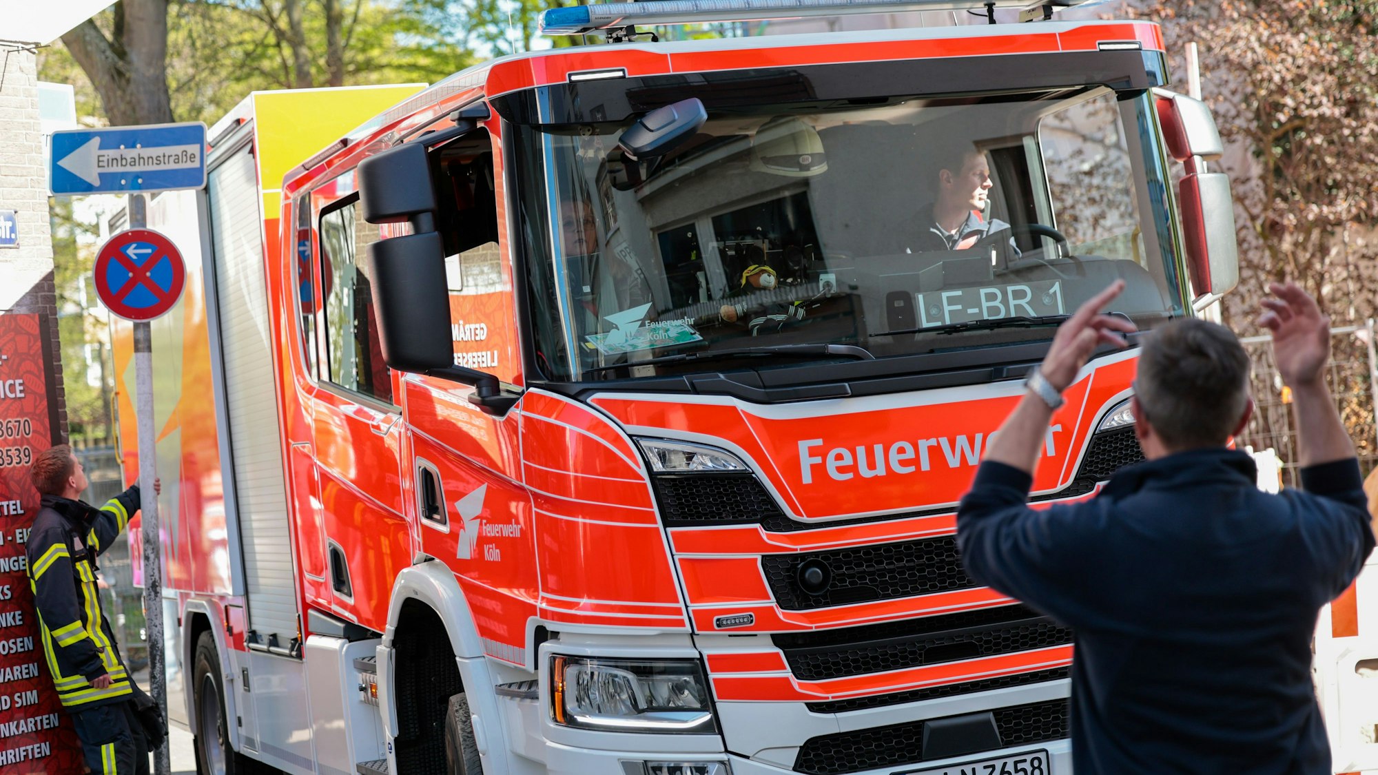 Ein Einsatzfahrzeug der Feuerwehr wird von einem Feuerwehrmann in einer engen Straße eingewiesen.