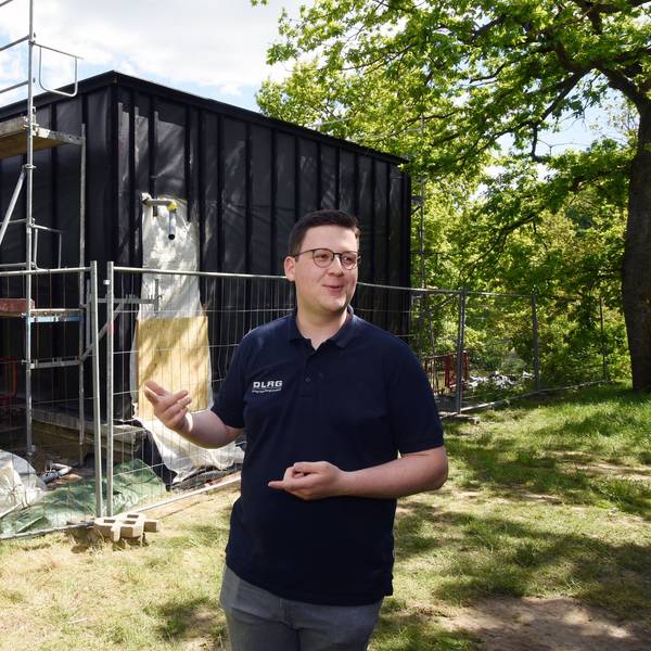 Das Foto zeigt den halbfertigen Neubau der Station, davor steht Philip Solbach von der DLRG.