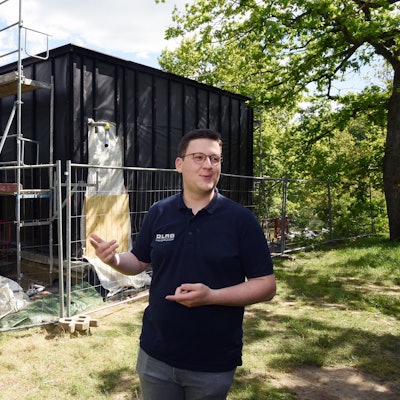 Das Foto zeigt den halbfertigen Neubau der Station, davor steht Philip Solbach von der DLRG.