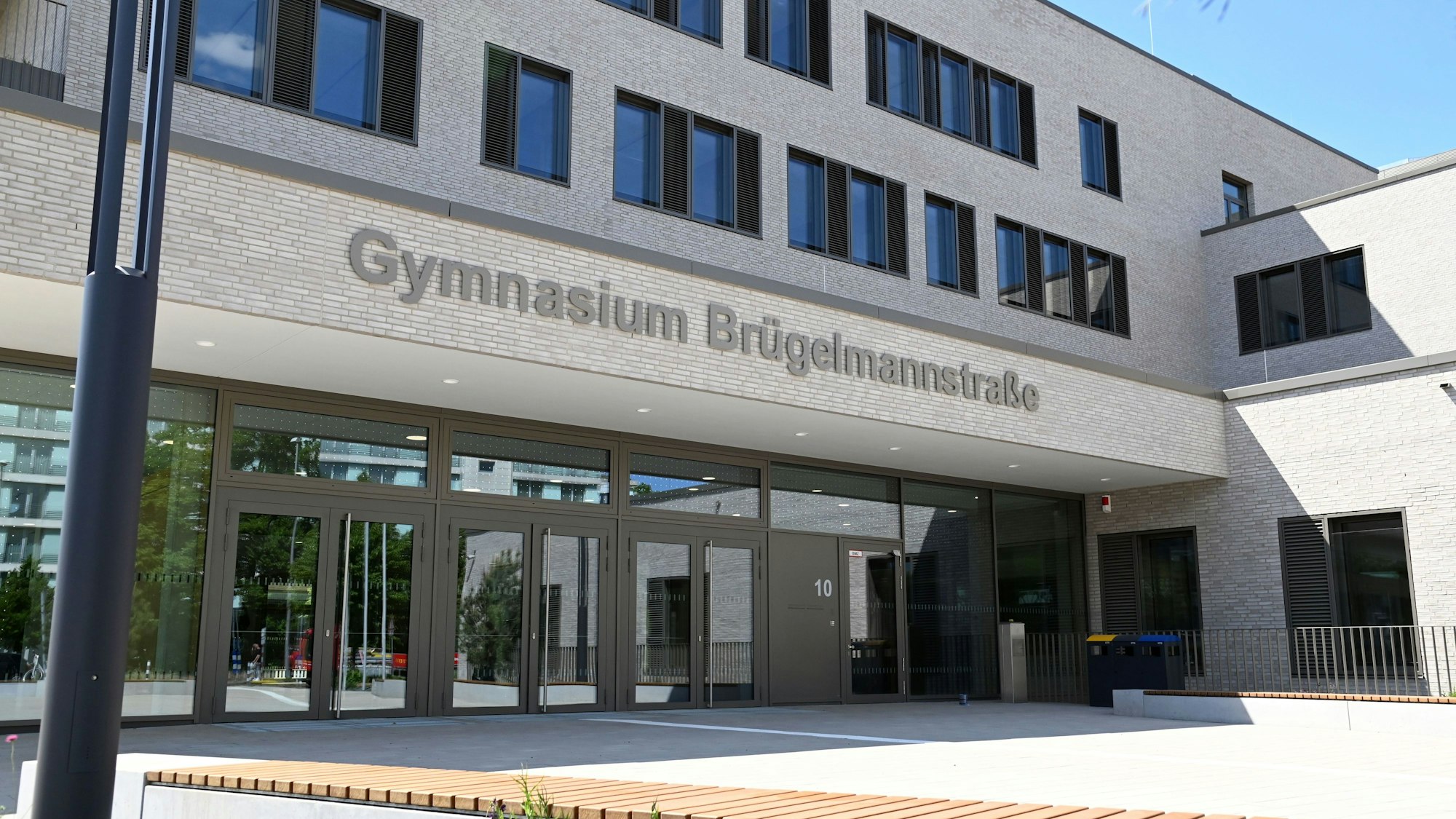 Blick auf ein modernes Gebäude, über dem Eingang prangt der Schriftzug Gymnasium Brügelmannstraße.