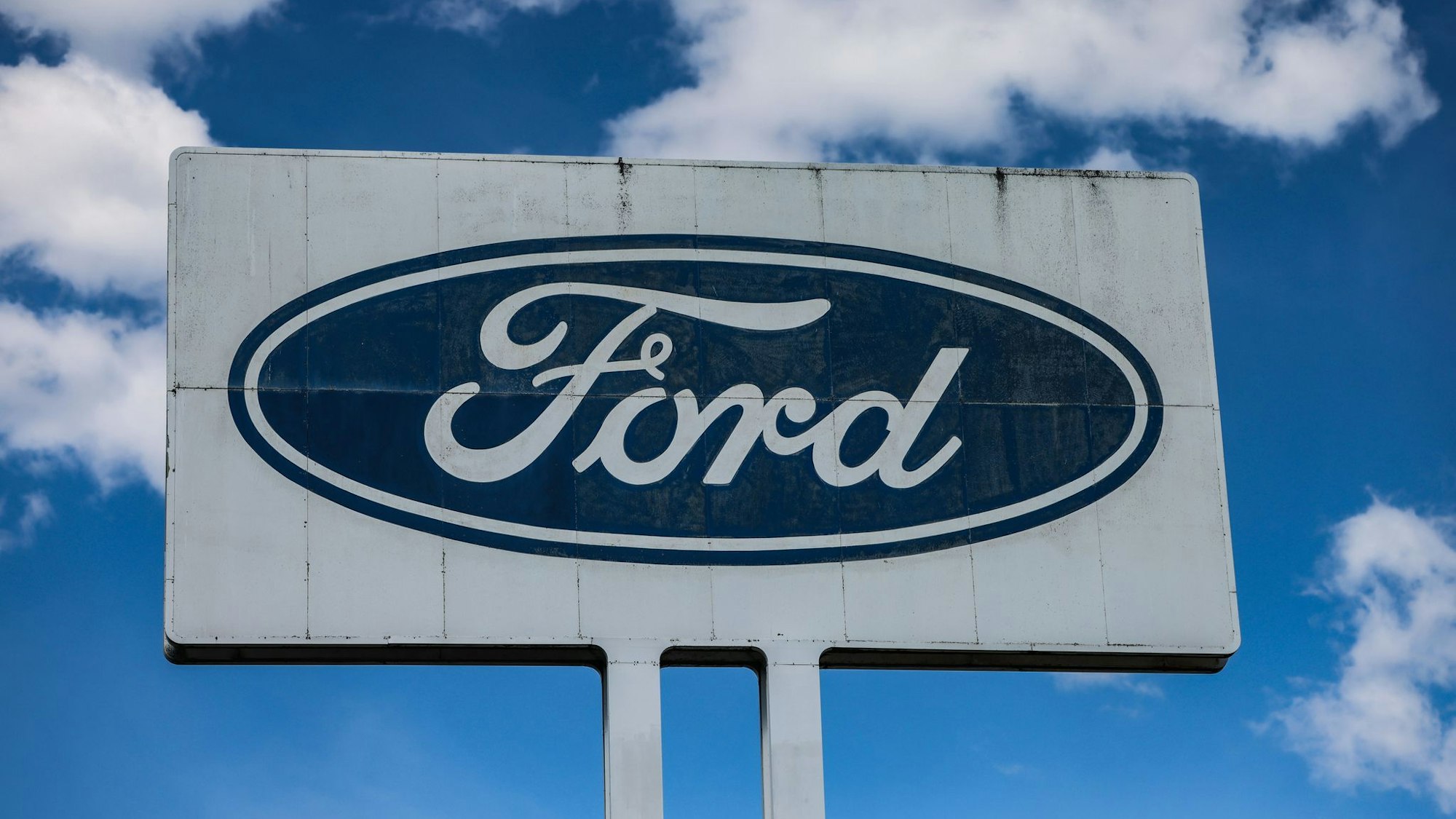 Ein Logo steht vor dem Ford Werk bei gutem Wetter - wirtschaftlich gesehen sind die Perspektiven des Ford-Autogeschäfts in Europa düster.