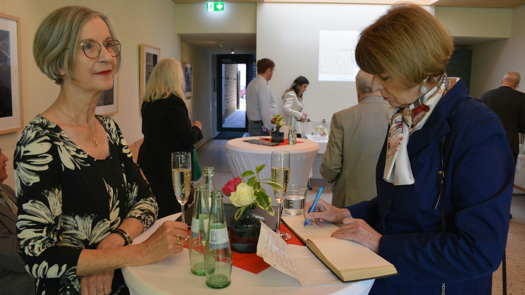 Claudia Weitekamp (l.) und Henriette Reker, die sich ins Gästebuch des Römergrab einträgt.
