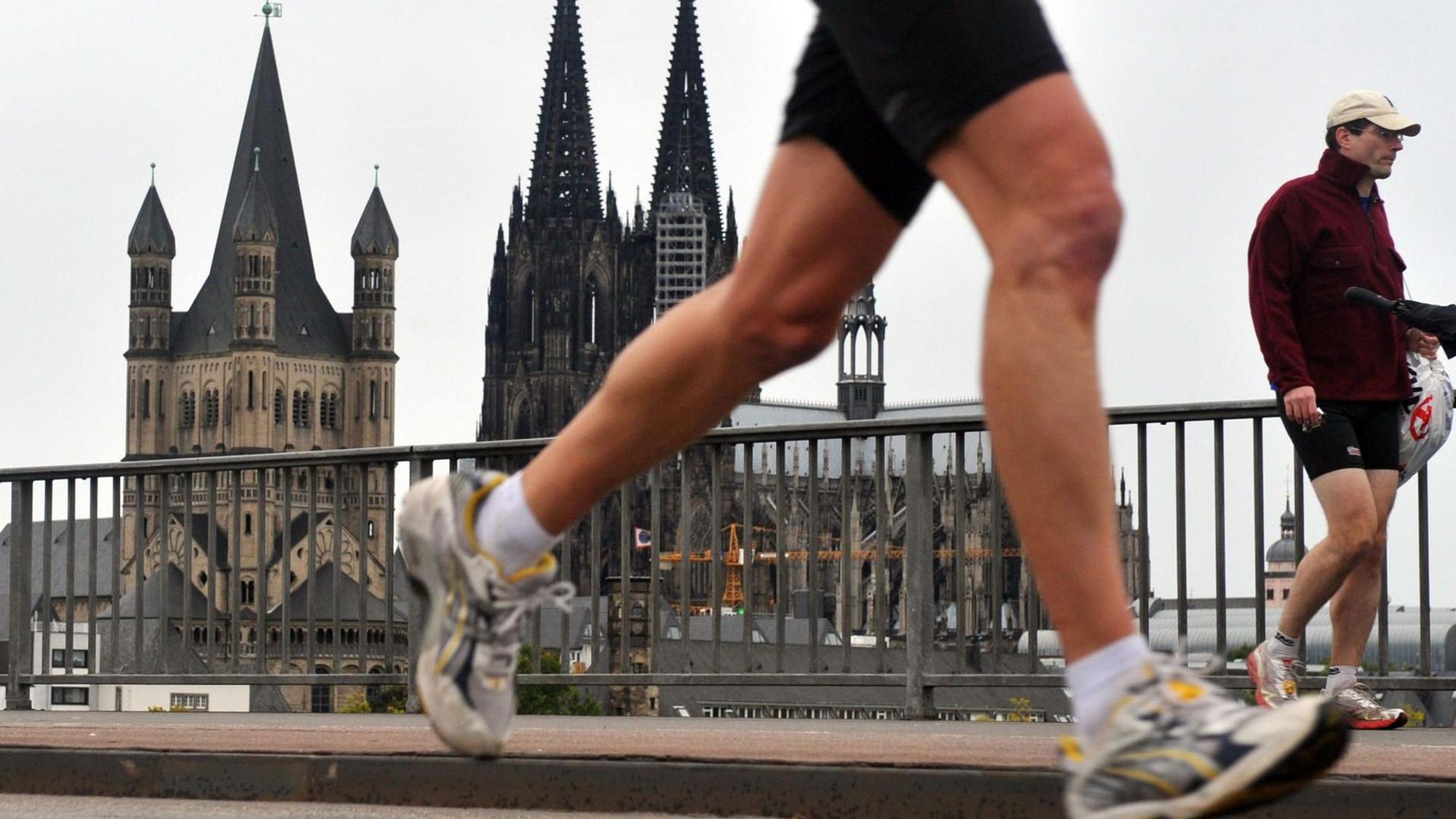 Ein Teilnehmer des Halbmarathons im Rahmen des Köln Marathons passiert vor der Kulisse des Doms die Deutzer Brücke.