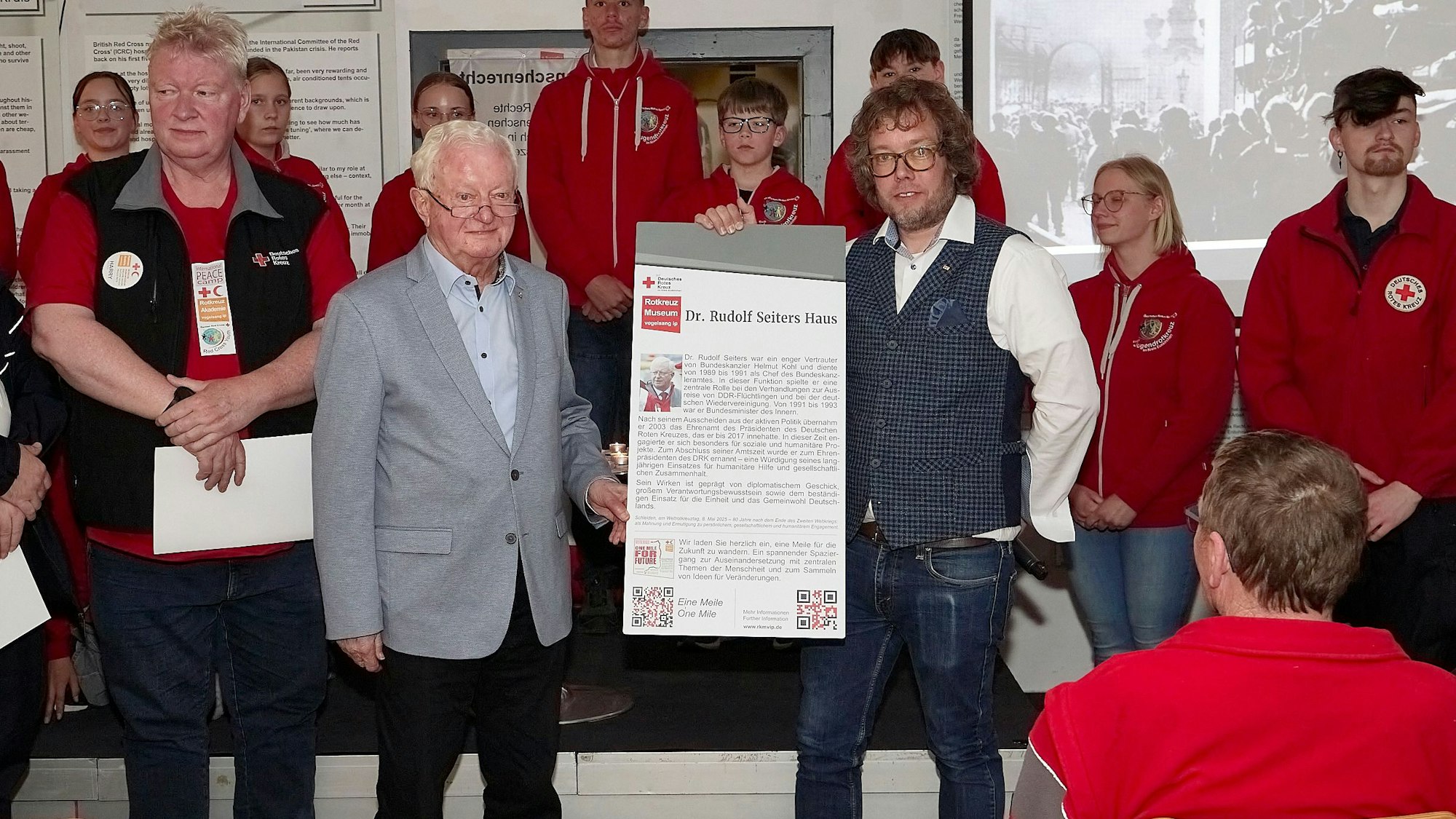 Simon Jägersküpper und Namenspate Dr. Rudolf Seiters halten ein Schild mit dem Namen Dr.-Rudolf-Seiters-Haus in den Händen.