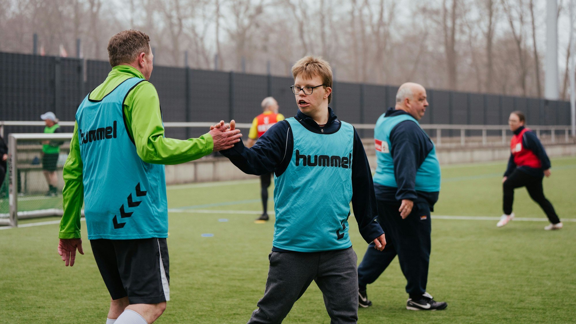 Auf dem Bild sind Sportler auf einem Rasenfeld zu sehen, die beim Inklusionssport des 1. FC Köln mitmachen.