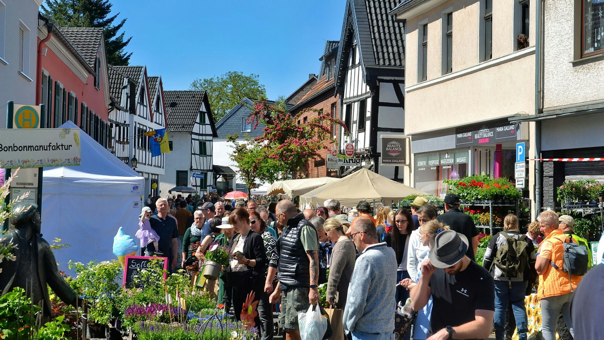 Menschenmassen schlendern entlang der Fachwerkhäuser in Kommern und schauen sich die Marktwaren an.