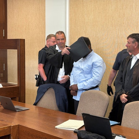 Der Angeklagte, hier mit seinen Verteidigern, wurde zunächst gefesselt in den Gerichtssaal geführt.