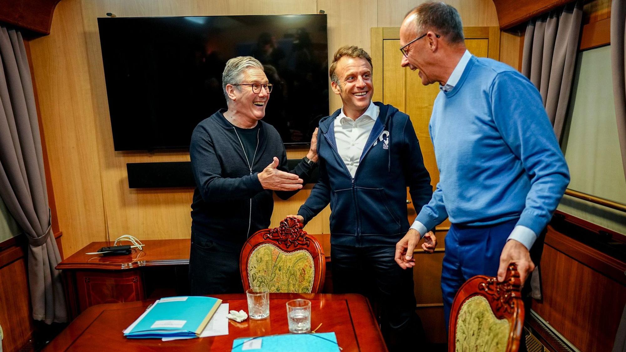 Bundeskanzler Friedrich Merz (r, CDU), Keir Starmer (l), Premierminister von Großbritannien, und Frankreichs Präsident Emmanuel Macron stehen im Salonwagen des Sonderzugs nach Kiew zusammen