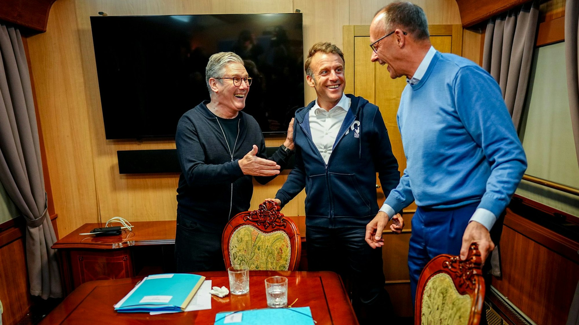 Bundeskanzler Friedrich Merz (r, CDU), Keir Starmer (l), Premierminister von Großbritannien, und Frankreichs Präsident Emmanuel Macron stehen im Salonwagen des Sonderzugs nach Kiew zusammen
