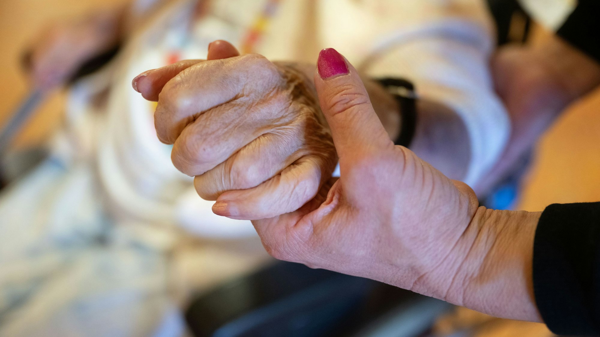 Eine Physiotherapeutin hält die Hand einer Pflegeheimbewohnerin. (Symbolbild)