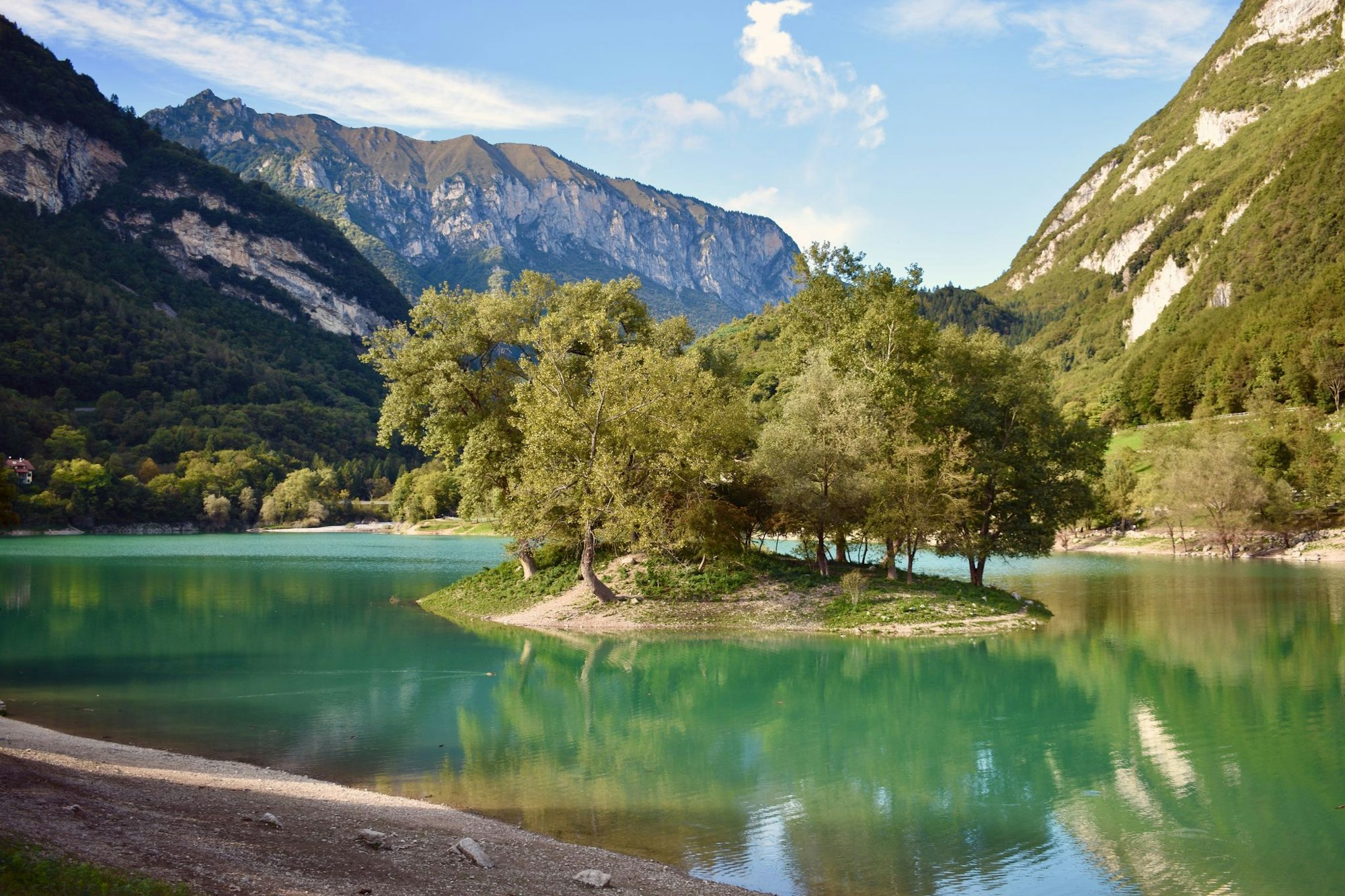 Im türkisblauen Wasser des Lago di Tenno liegt diese winzige, bewaldete Insel.