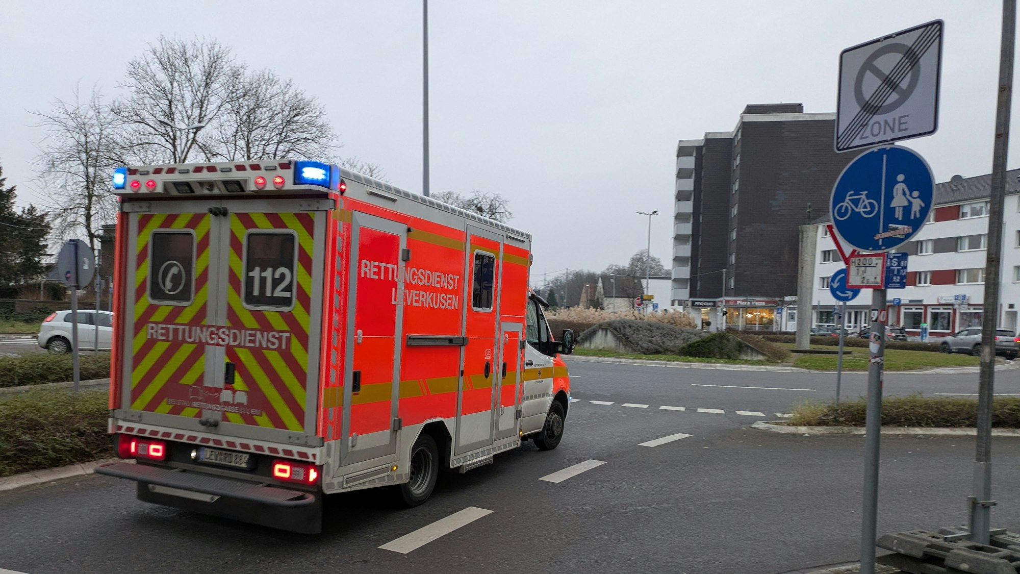Ein Rettungswagen fährt mit Blaulicht auf den Berliner Platz in Opladen.