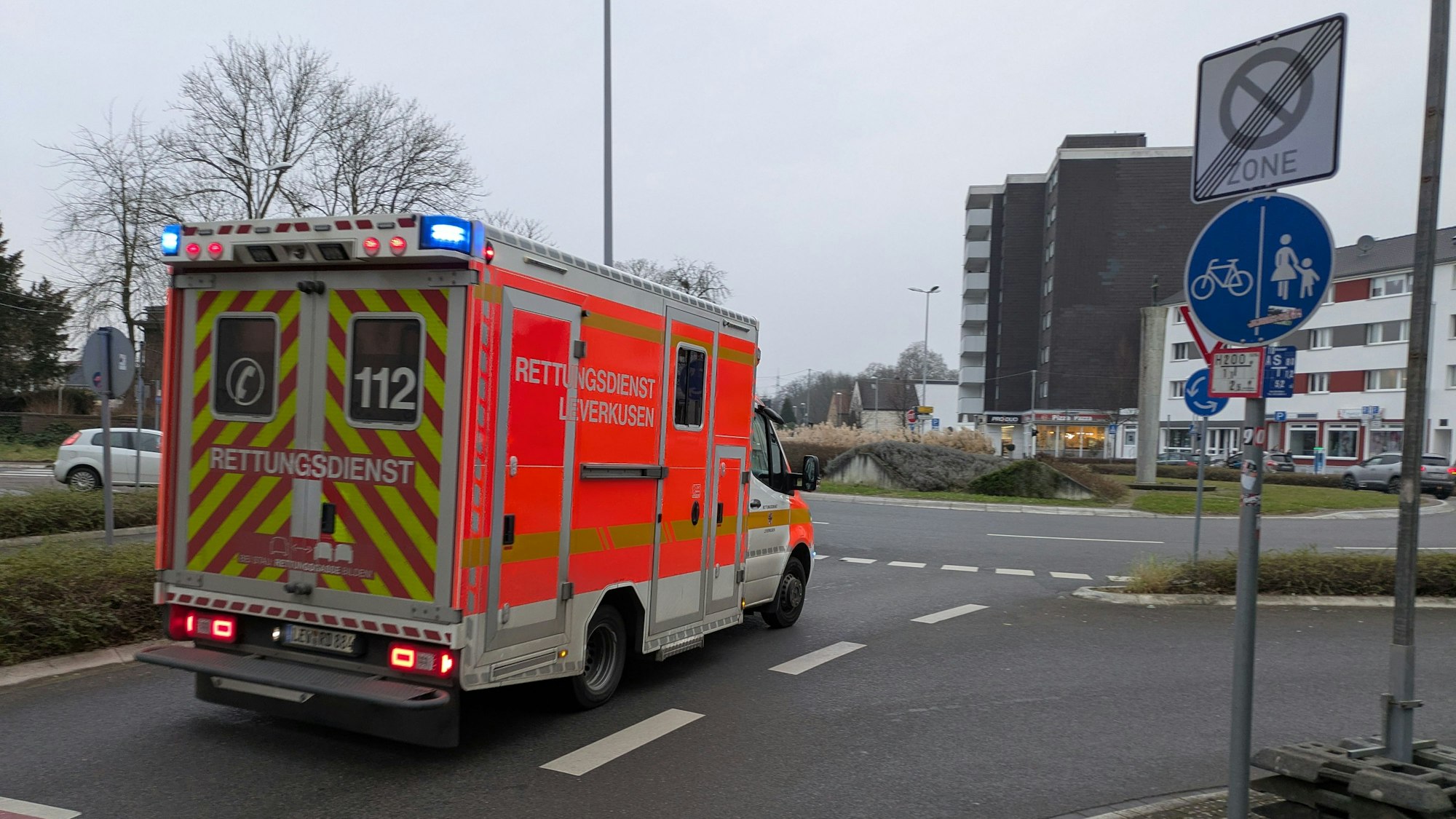 Ein Rettungswagen fährt mit Blaulicht auf den Berliner Platz in Opladen