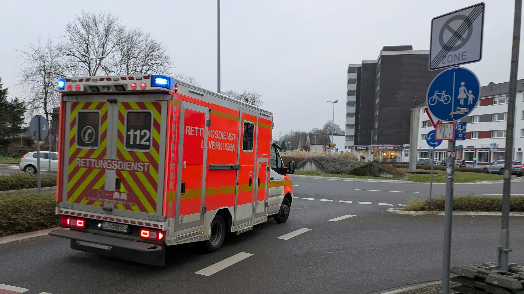 Ein Rettungswagen fährt mit Blaulicht auf den Berliner Platz in Opladen.
