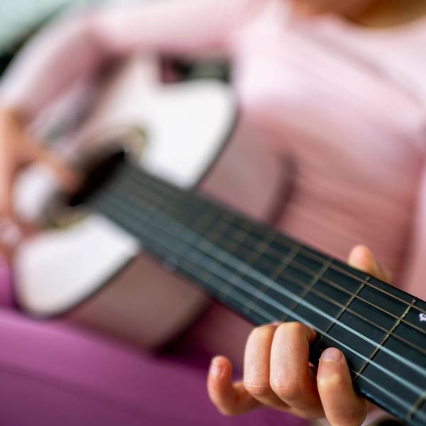 Das Symbolfoto zeigt ein Kind, das Gitarre spielt.
