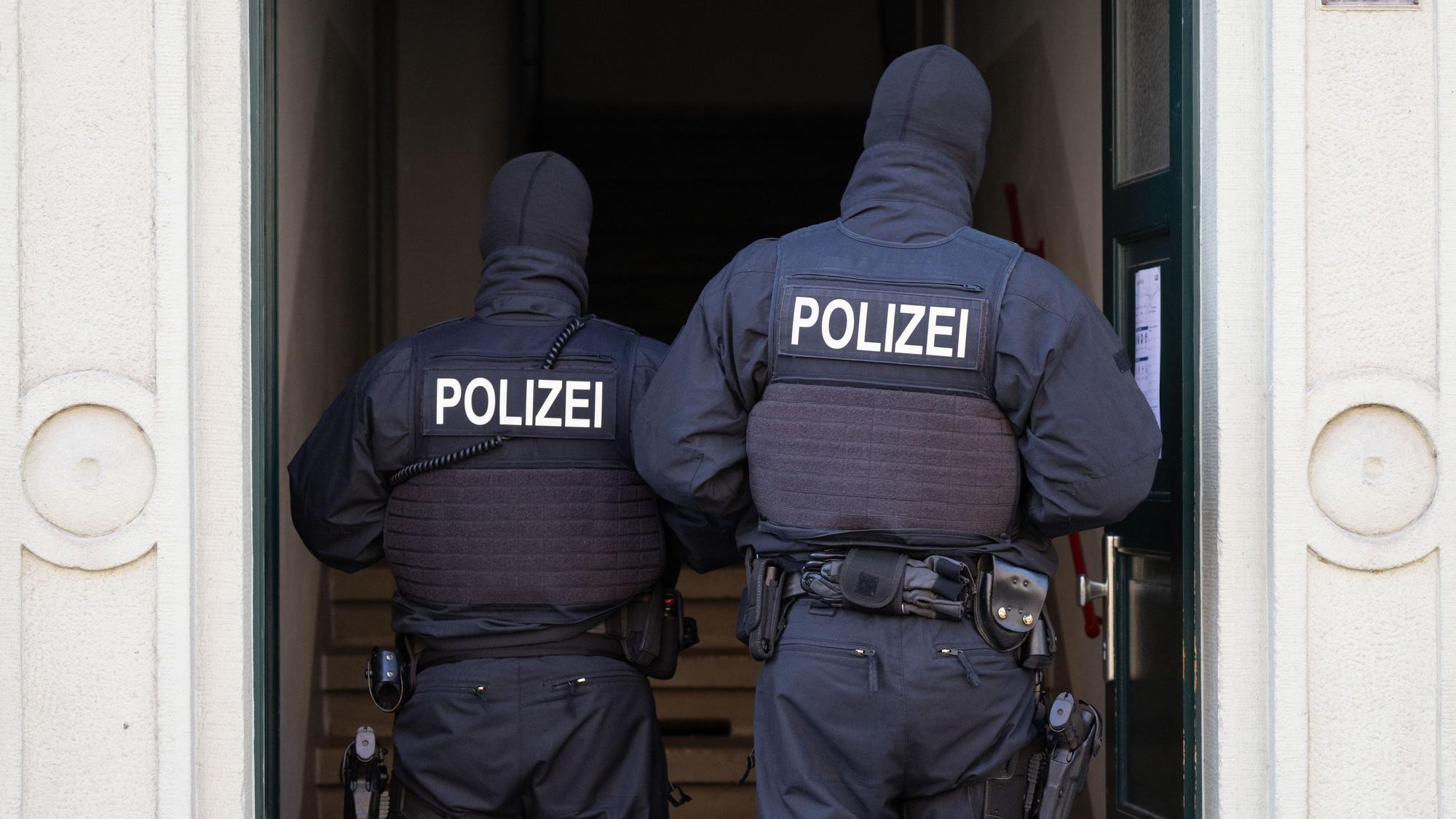 Polizisten stehen während einer Razzia gegen mutmaßliche Rechtsextreme in einem Hauseingang im Dresdner Stadtteil Cotta.