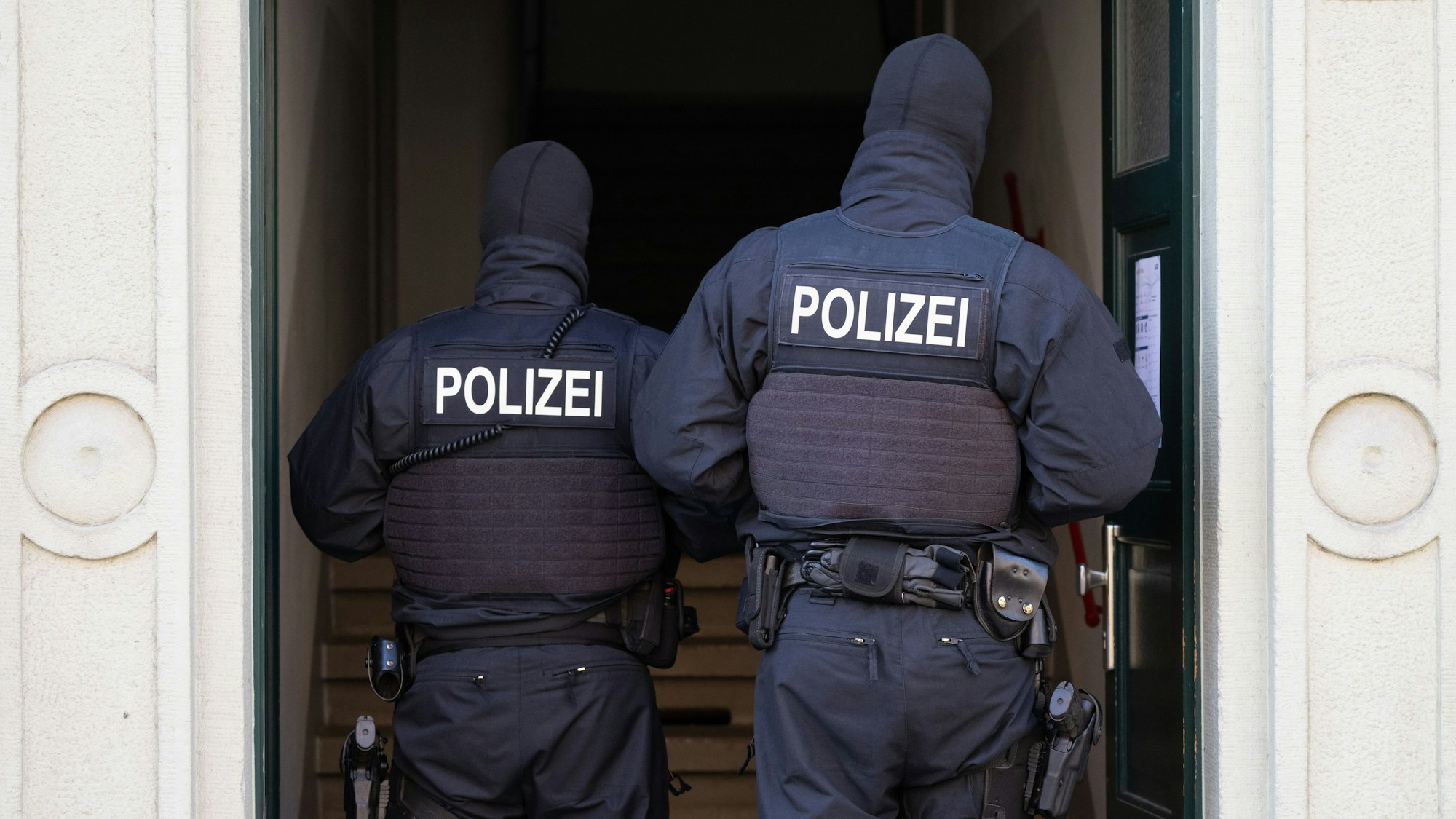 Polizisten stehen während einer Razzia gegen mutmaßliche Rechtsextreme in einem Hauseingang im Dresdner Stadtteil Cotta. (Archivbild)