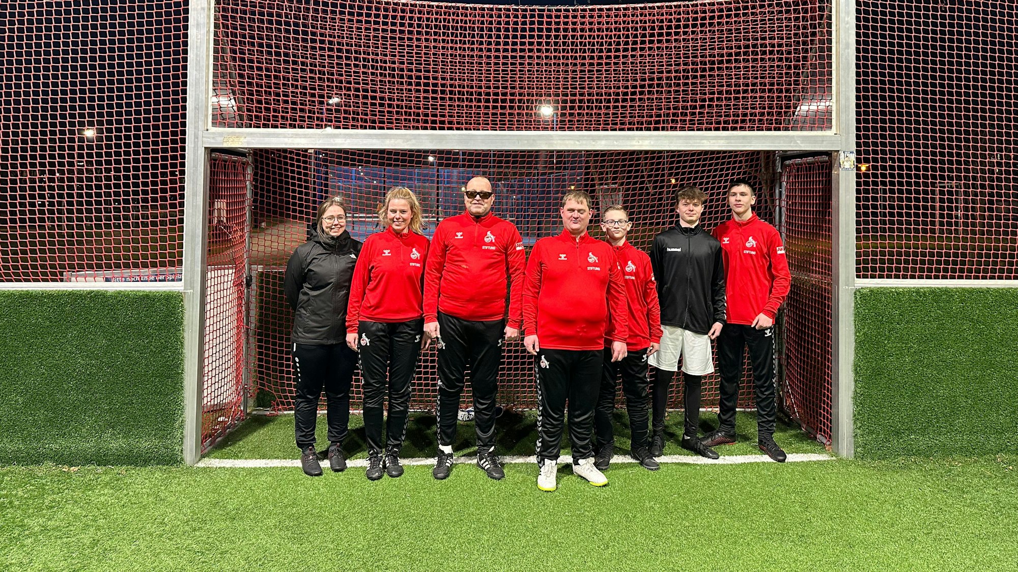 Auf dem Bild sind Trainer und Spieler der Blindenmannschaft zu sehen, die in einem Tor stehen.