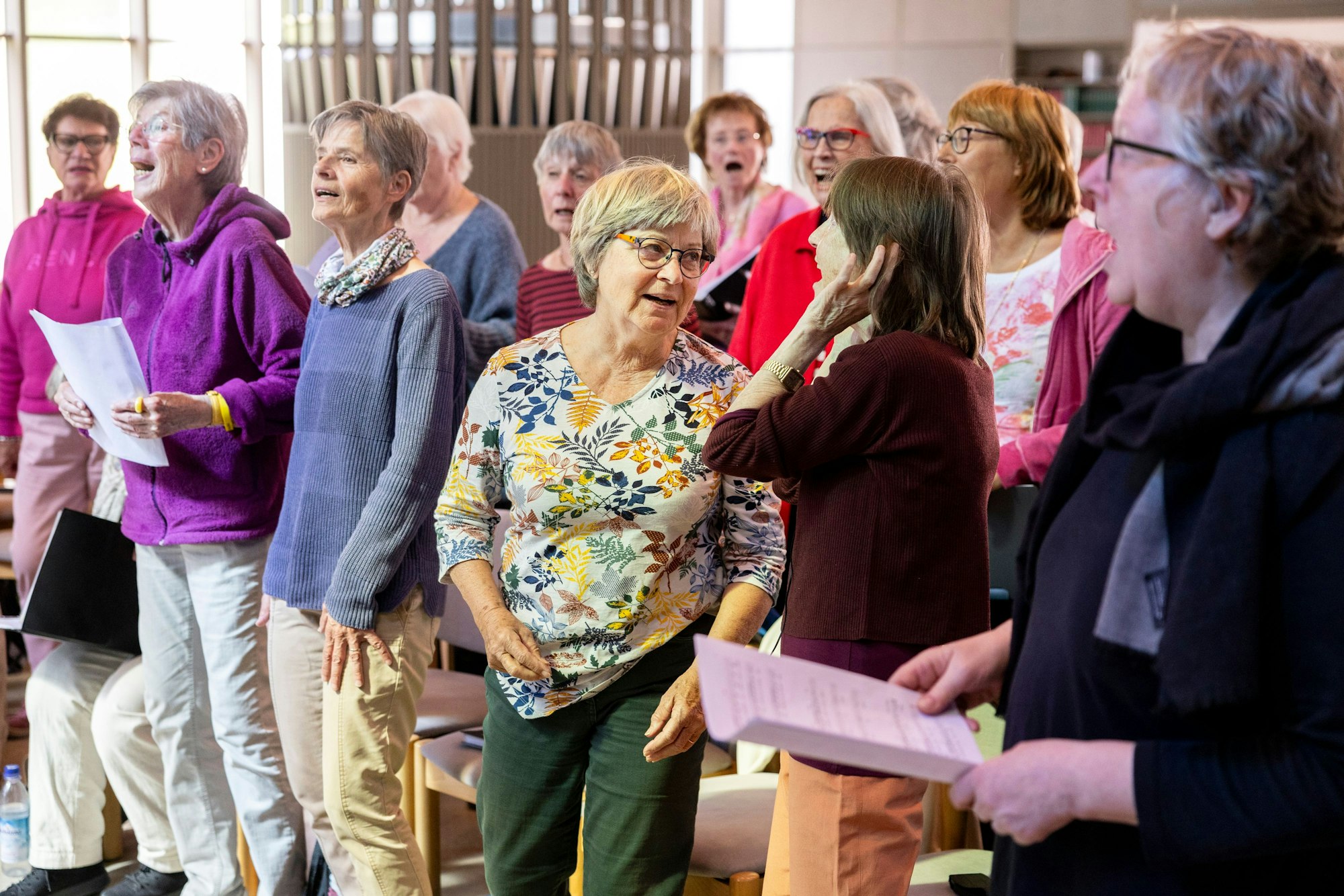 Die Chormitglieder sind singend zu sehen. Einige halten Noten in der Hand.