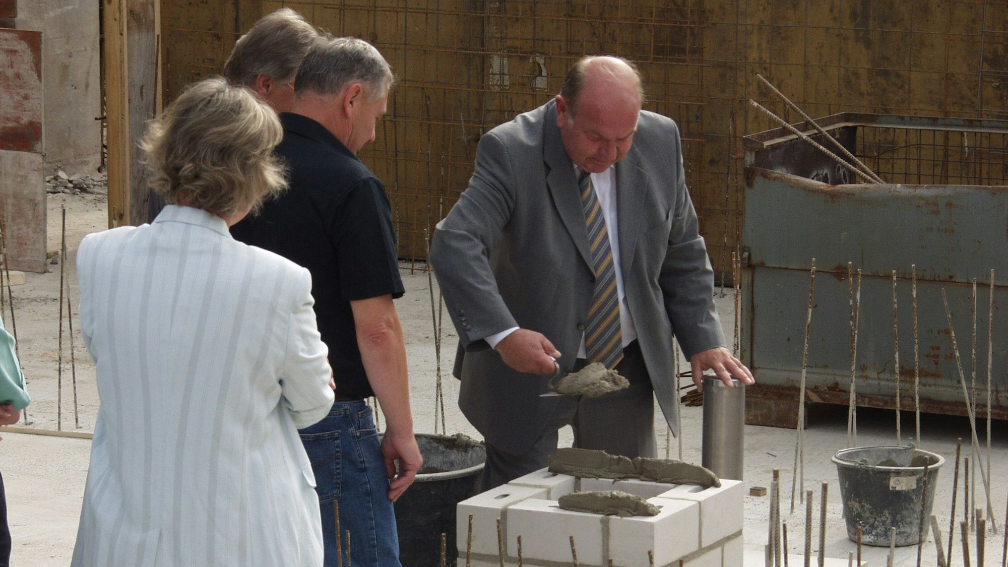 Auf dem Bild ist die Grundsteinlegung für den Erweiterungsbau der Schule zu sehen. Er fand 2002 statt.