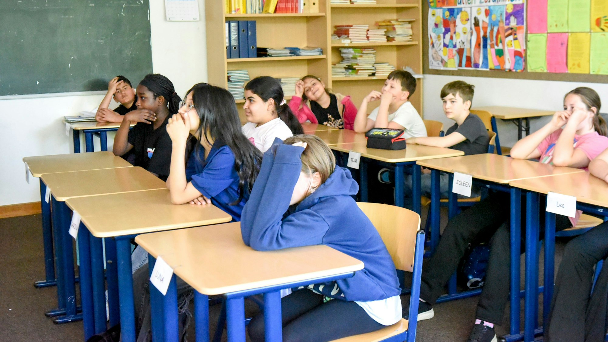 Auf dem Bild sind Schulkinder an Tischen in ihrem Klassenzimmer zu sehen.