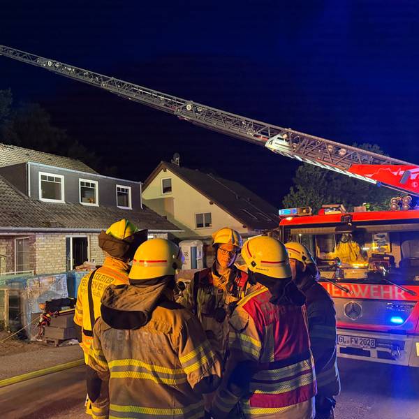 Eine Drehleiter der Feuerwehr Bergisch Gladbach steht an einem Haus im Alten Traßweg in Bergisch Gladbach-Kippekausen. Feuerwehrleute stehen davor.