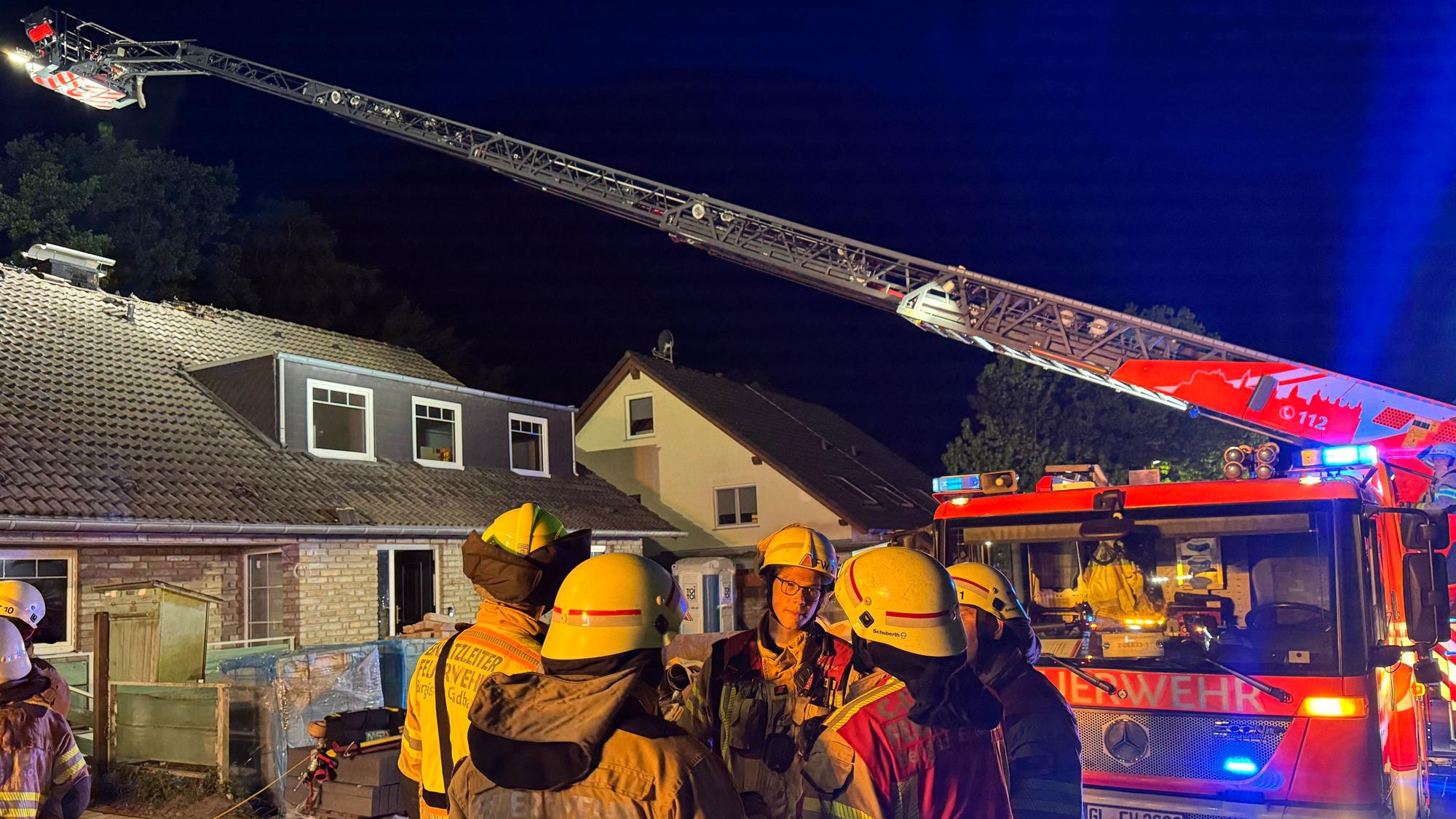 Eine Drehleiter der Feuerwehr Bergisch Gladbach steht an einem Haus im Alten Traßweg in Bergisch Gladbach-Kippekausen. Feuerwehrleute stehen davor.