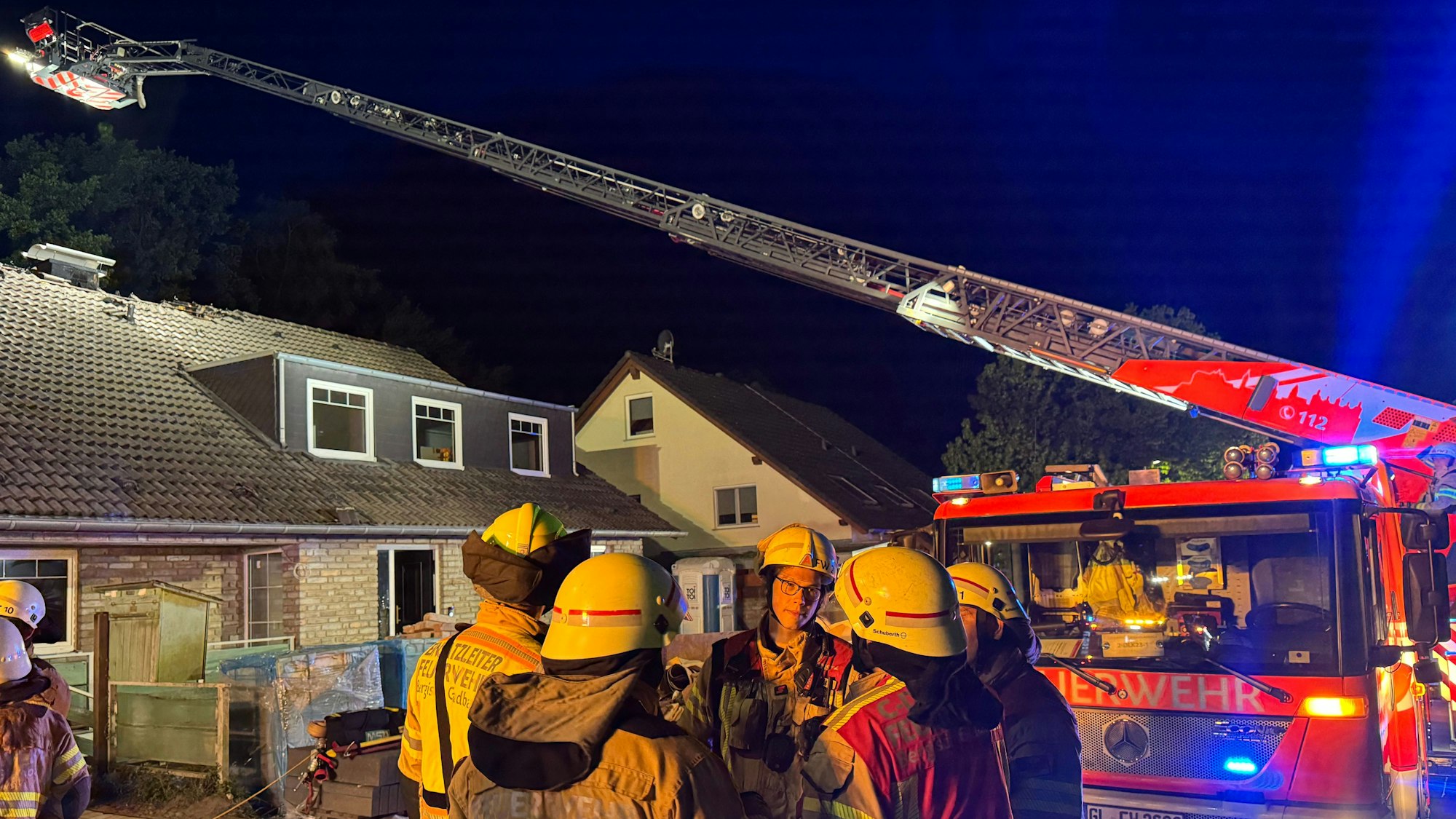 Eine Drehleiter der Feuerwehr Bergisch Gladbach steht an einem Haus im Alten Traßweg in Bergisch Gladbach-Kippekausen. Feuerwehrleute stehen davor.