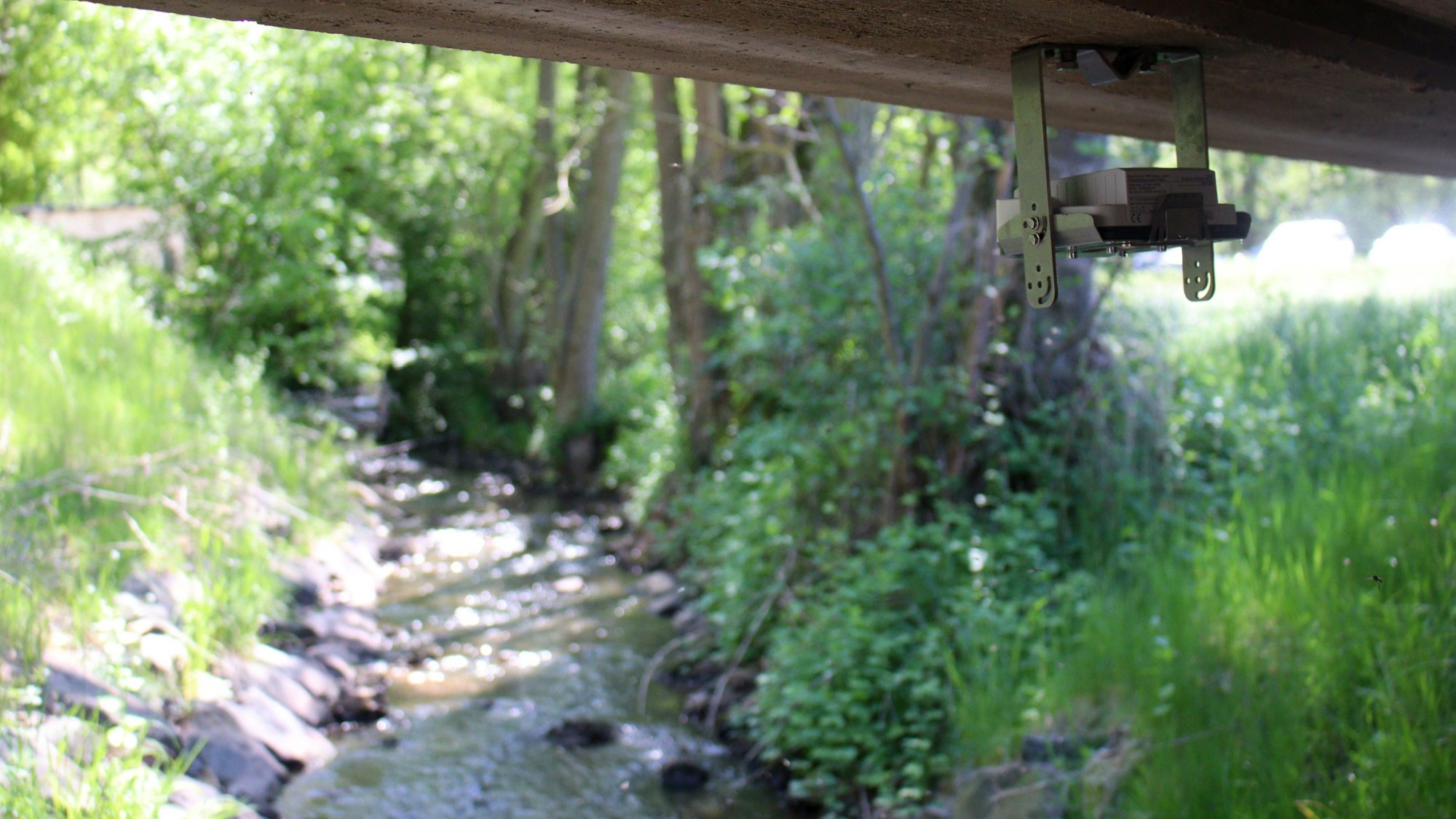 Eine kleine Kamera ist unter einer Brücke installiert. Unten fließt der Eschweiler Bach mit niedrigem Wasserstand.