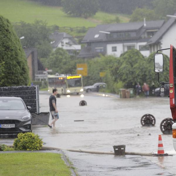 Zu sehen ist eine überflutete Straße, davor ein Fahrzeug der Feuerwehr.