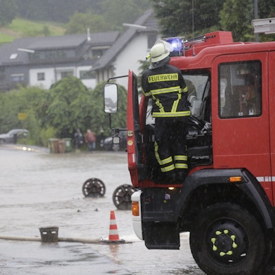 Zu sehen ist eine überflutete Straße, davor ein Fahrzeug der Feuerwehr.