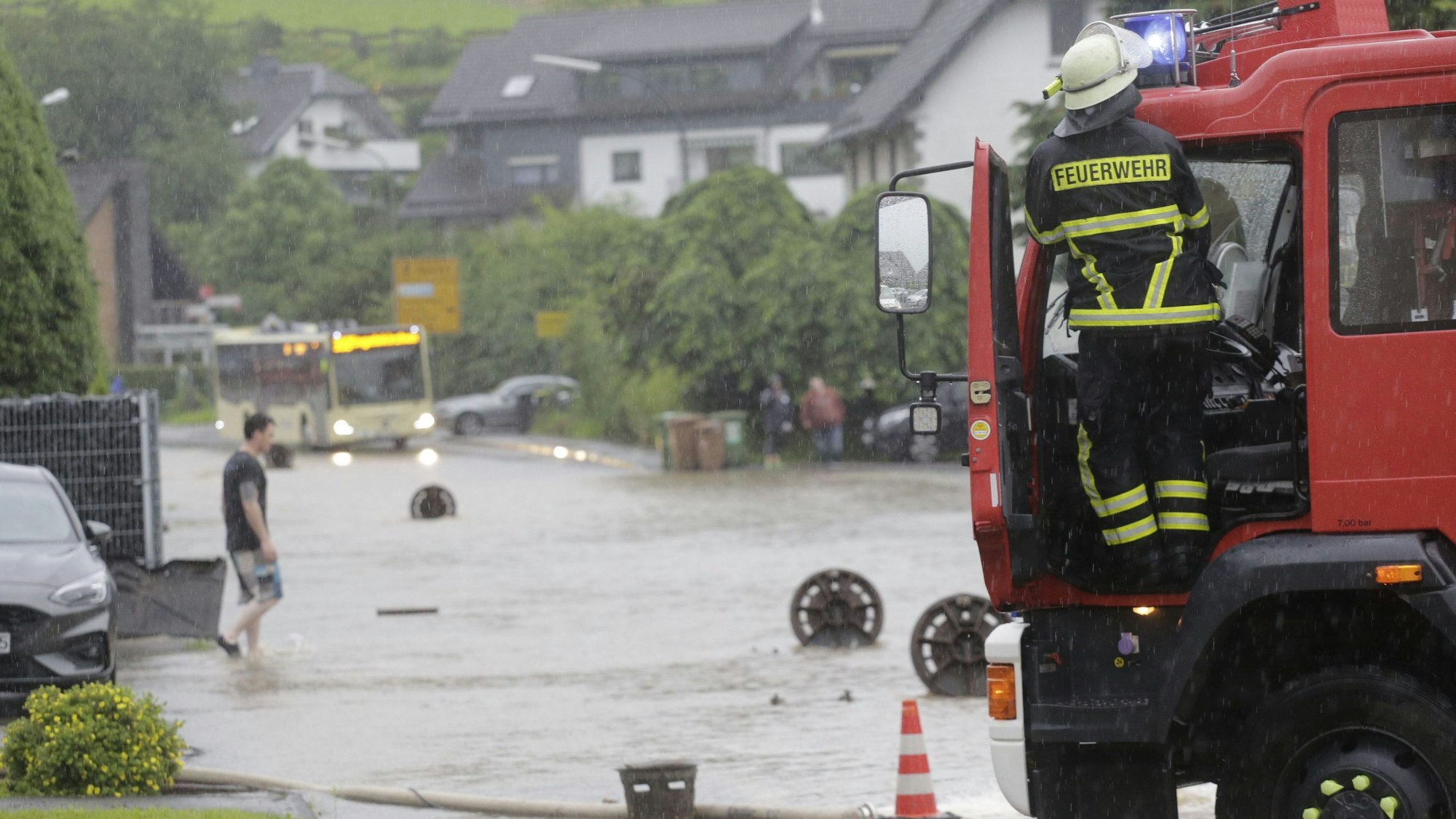 Zu sehen ist eine überflutete Straße, davor ein Fahrzeug der Feuerwehr.