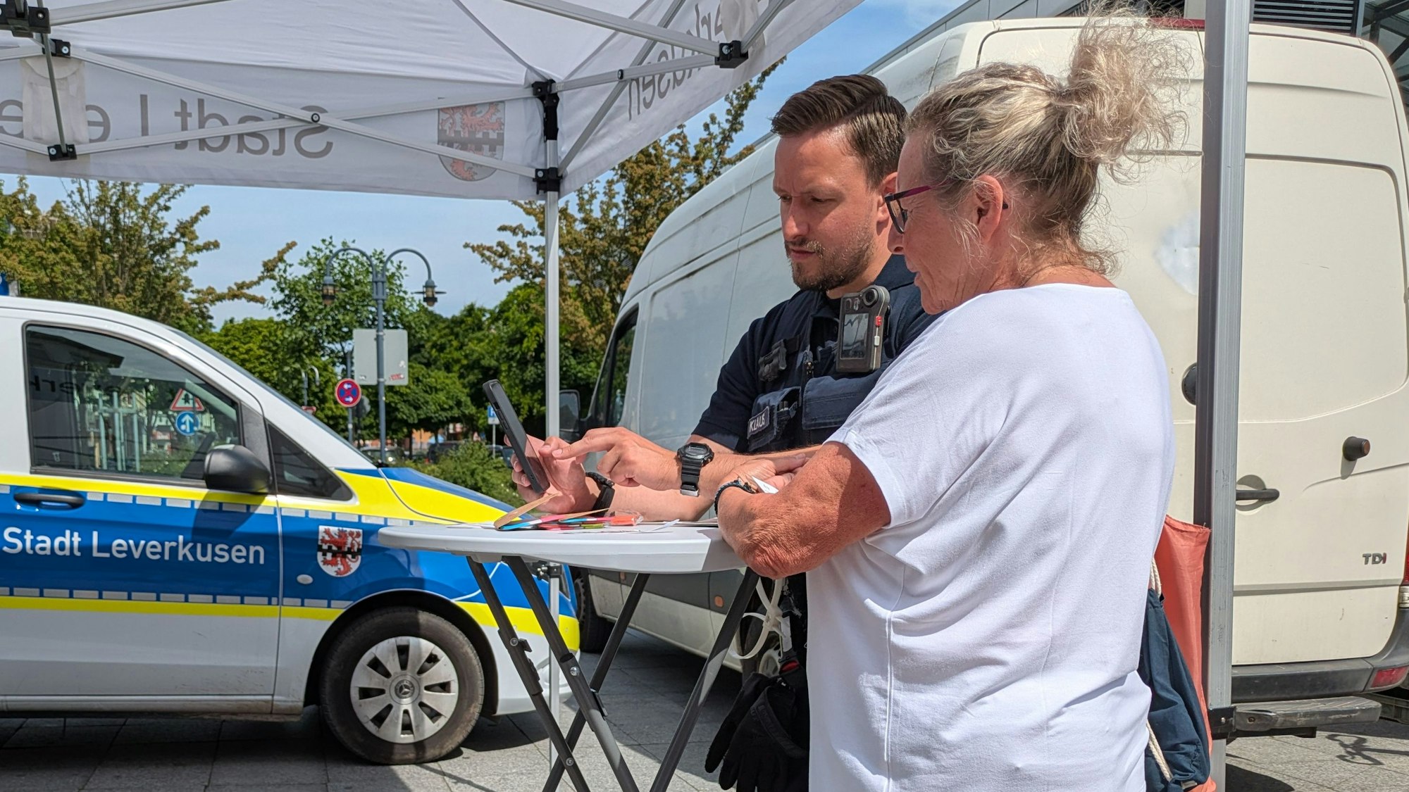 Ein Mann und eine Frau unterhalten sich an einem Stand der Stadt Leverkusen.